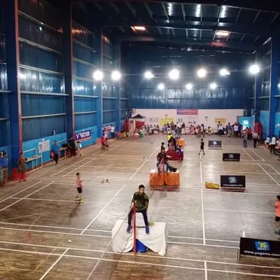 Our facility is fully equipped to host large-scale badminton tournaments. This wide shot shows our courts set up for a competition, complete with umpire chairs, spectator seating, and official branding.