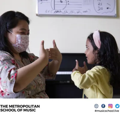 An instructor and a young student share a moment of connection during a music lesson. We create a fun, safe, and educative environment for children, with lessons available on weekends.