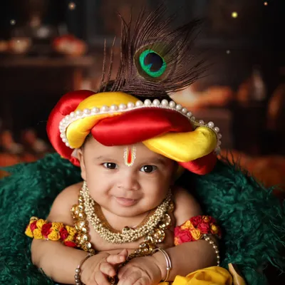 A close-up of a smiling baby Krishna. The peacock feather in his mukut and the pearl necklaces complete this divine look. It’s a joy to create these special Janmashtami portraits.