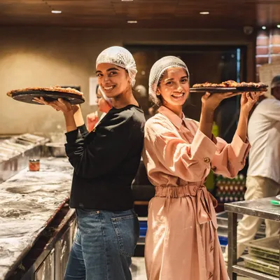 Two happy participants in our pizza making workshop, proudly holding up their finished creations. Making pizza is fun, but eating your own creation is pure love.