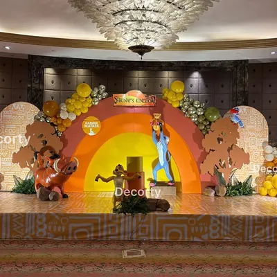 The complete stage setup for a grand 'Lion King' themed birthday party. The scene features a vibrant Pride Rock backdrop, life-sized character models of Mufasa, Pumbaa, and Timon, and themed flooring to create an immersive experience.