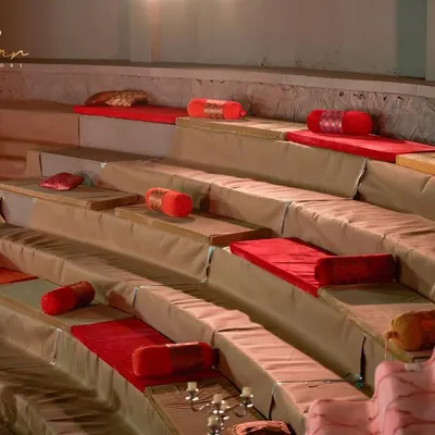 For a traditional and comfortable guest experience, I designed this baithak-style seating in an amphitheater. The red and gold cushions, along with elegant candelabras, create a regal and inviting atmosphere.