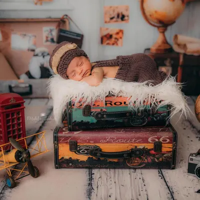 A wide shot of the 'little traveler' newborn setup. This image shows how I combine props like vintage suitcases, a globe, and a toy plane to build a complete, story-driven scene.