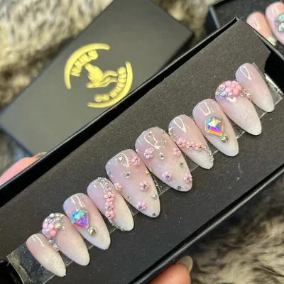 A beautiful almond-shaped press-on set designed for a special occasion. This design features a soft pink and white base with delicate 3D flowers, silver beads, and large iridescent crystals for a touch of glamour.