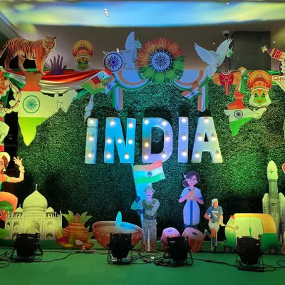 I create large-scale patriotic decor for corporate offices and community events. This Republic Day stage features a massive "INDIA" marquee sign against a green backdrop, surrounded by cutouts representing our country's diverse culture and achievements.