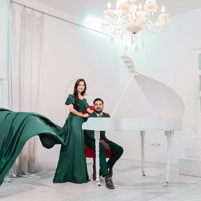 An elegant and dramatic studio shot featuring a grand piano and a beautiful flowing dress. This setup is perfect for couples who want a touch of high-fashion glamour.