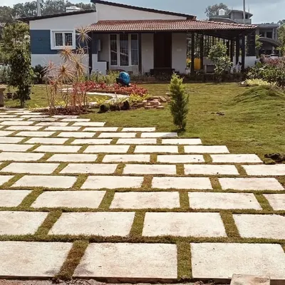 A farmhouse landscape in its final stages. The stone paver driveway is complete, and fresh turf has been laid, with planters and garden beds ready for final touches.