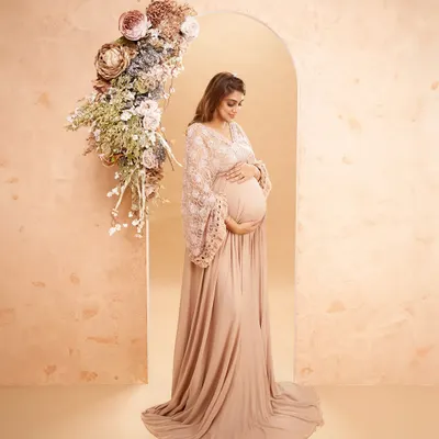 A beautiful portrait featuring a custom-built floral arch. The warm, peach-toned backdrop and elegant gown come together to create a sophisticated and artistic floral-themed shot.