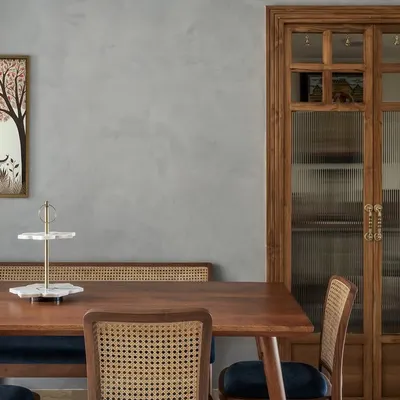 This serene puja room in our 'Malhar' project was created by reconfiguring a section of the dining room. The space is enclosed with elegant fluted glass panels and wooden shutters, offering a blend of privacy and visual lightness.