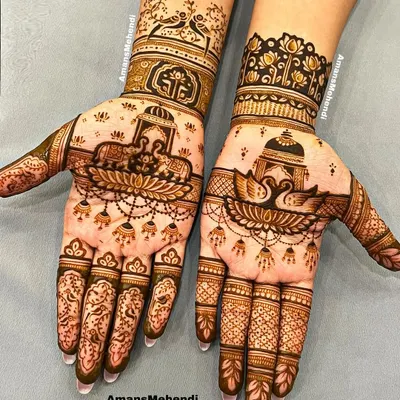 A beautiful example of asymmetrical bridal design. One hand features majestic elephants and a lotus, while the other showcases graceful swans, both incorporating traditional jharokha elements.