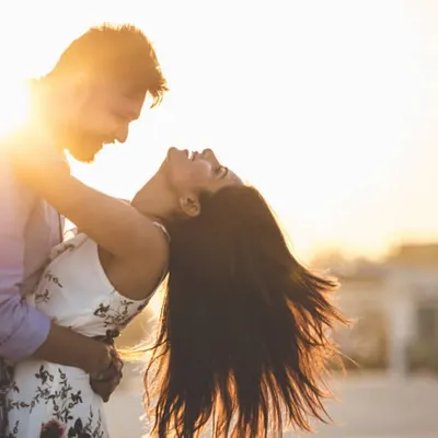 The perfect golden hour shot. This image captures the pure, unadulterated joy of a couple sharing a laugh, with the setting sun creating a warm, magical glow.