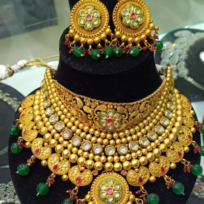 This bridal necklace set has a beautiful antique gold finish with detailed meenakari work in green and pink. The matching earrings with green bead drops complete this traditional look, making it feel like authentic gold jewellery.
