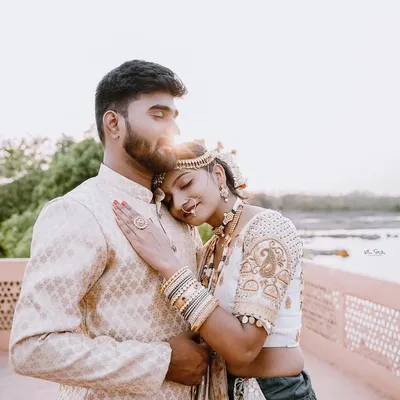A truly romantic and serene moment from a royal pre-wedding shoot. The bride rests her head on the groom's shoulder as the sun sets behind them, creating a beautiful flare and a feeling of pure peace and love.