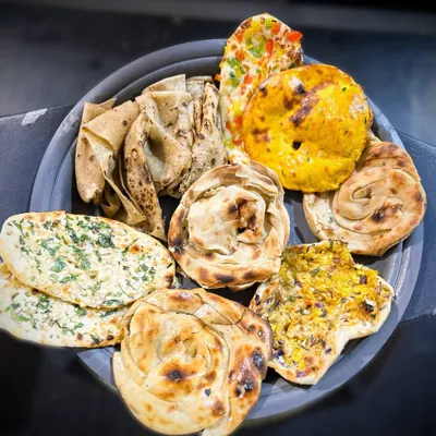 A platter showcasing the irresistible variety of Indian artisanal breads I offer. Each one, from the Missi Roti to the Lachha Paratha, is crafted to perfection to complement your main course.