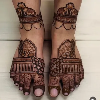 A perfect example of regal foot mehndi. This symmetrical design features majestic peacocks on the top of the feet and a band of elephants around the ankles.