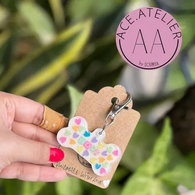 A custom dog tag for a very good boy or girl. This bone-shaped resin tag is filled with colorful heart confetti and can be personalized with your pet's name.
