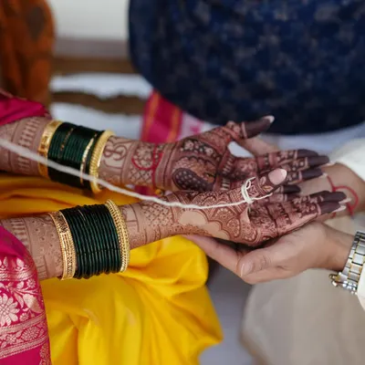 The beauty of a rich henna stain during a wedding ceremony. The deep maroon color of the mehendi contrasts beautifully with the bride's yellow saree and green bangles.