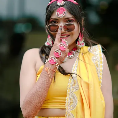 A fun and playful Haldi bride. For this look, I kept the makeup fresh and dewy with a pop of pink on the eyes, complementing her yellow outfit and floral jewelry.