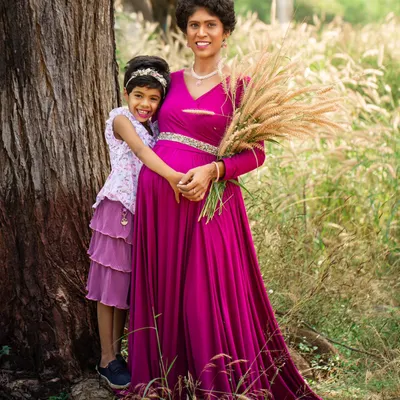 A mother and daughter share a hug in a sunlit field. This outdoor maternity photo uses the natural beauty of the surroundings to create a warm and intimate portrait.