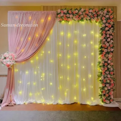 An elegant photo backdrop created with drapes and artificial flowers. I used a combination of white and pink fabric with warm fairy lights and a floral border for a soft, classic look.