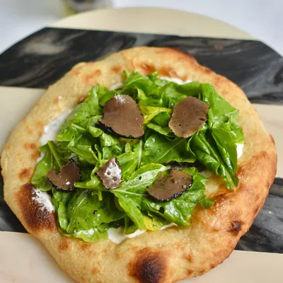 Our Truffle Sourdough Flatbread from the "Spain comes to Maska" pop-up. A simple yet luxurious treat featuring fresh arugula and shaved truffle on our house-made sourdough.