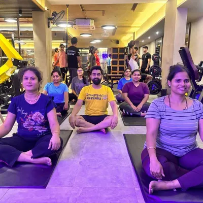 A group of members in a yoga class, seated in a meditative posture. These sessions are designed to improve flexibility, build core strength, and provide a peaceful end to a busy day.