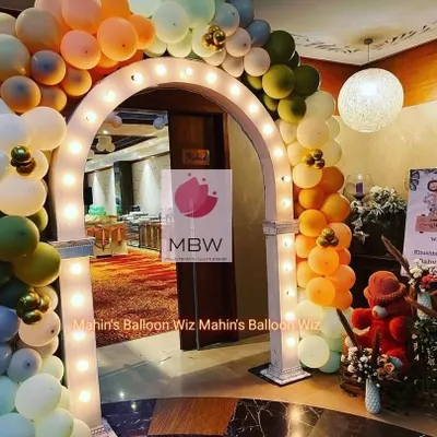 A beautiful light-up entrance arch decorated with a balloon garland in modern, earthy tones. This creates a warm and inviting welcome for guests as they arrive.