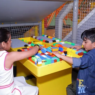 Two children collaborate at the Lego table, building colorful structures and developing teamwork skills.