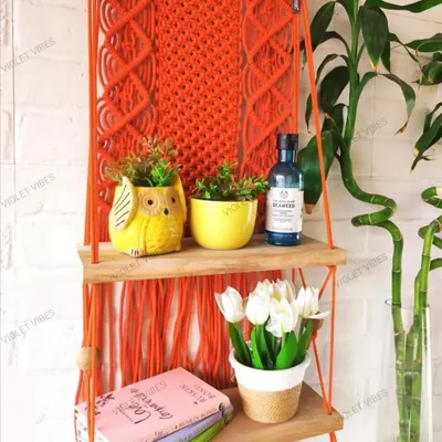 This two-tiered hanging shelf in a vibrant orange is perfect for displaying multiple small plants and decor items. It adds both functionality and a pop of color to this bright corner.
