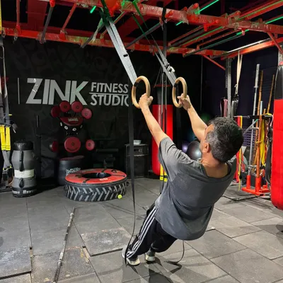 A member demonstrates incredible upper body and core strength on the gymnastic rings. This advanced equipment is available for clients looking to take their bodyweight training to the next level.
