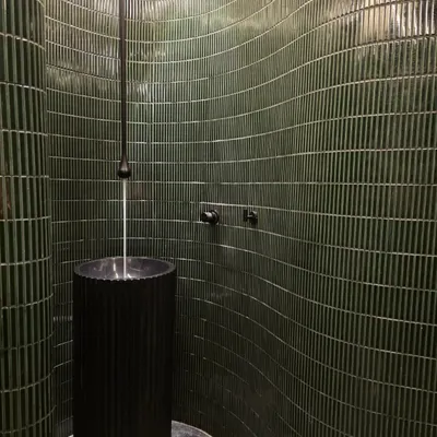 I'm not afraid of a little drama, and this powder bathroom is proof. The curved wall with deep green, textured tiles and a sleek pedestal sink creates a moody, unforgettable statement.