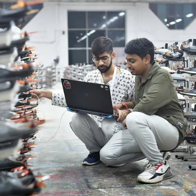 Collaboration is key to our innovation. Here, two of our engineers are running diagnostics on our drone racks, cross-checking flight data on a laptop. This teamwork ensures every single drone in the fleet is perfectly calibrated and ready for the show.