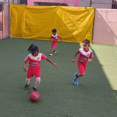 Action in full swing! A young player focuses intently on dribbling the ball during a practice match. Our classes are designed to build ball control and confidence in game-like situations.