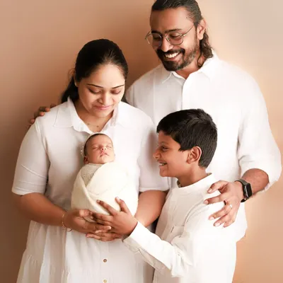 A family of four, full of smiles. The older brother looks at his new baby sibling with so much love and pride. Capturing these sibling moments is truly special.