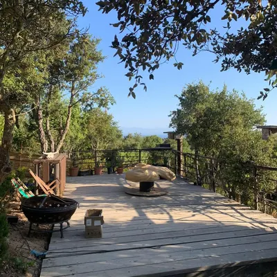 The spacious wooden deck at our Italy retreat location in Sardinia, surrounded by trees with a view of the sea. This is where we practice our morning asanas and evening meditation.
