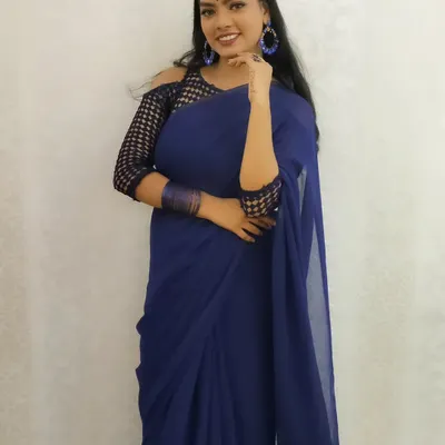 A modern and chic party look featuring a stunning royal blue saree. The makeup is bold and confident, with a focus on flawless skin and matching blue accessories.