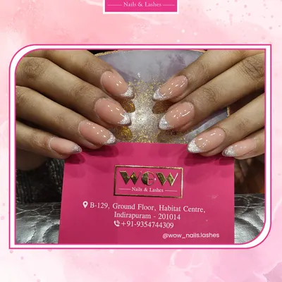 A flawless classic French manicure on elegant, almond-shaped nails. The glittery silver line adds a subtle, modern sparkle to this timeless design.