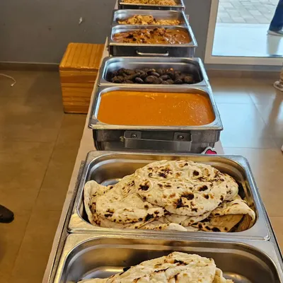 A full buffet line ready for service. This spread includes a variety of Indian main courses like dal makhani and paneer, served with fresh naan bread.