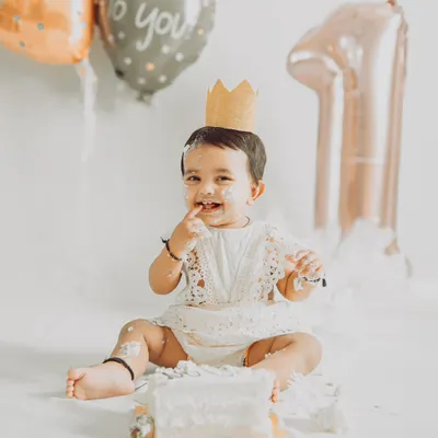 A perfect first birthday moment: a cute crown, a delicious cake, and a happy, messy baby. This is the heart of a cake smash session, capturing that priceless expression of sweet discovery.