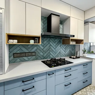 This L-shaped kitchen features a beautiful herringbone tile backsplash. The combination of powder blue and white cabinets with matte black hardware creates a fresh, contemporary look.
