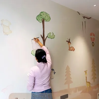 A full view of the nursery mural in progress. You can see the gentle landscape and the placement of the various woodland animals, all coming together to create a whimsical world.