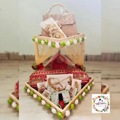 This wedding hamper was designed with a beautiful mandap theme. I used a tiered wooden tray decorated with green and white pom-poms to artfully arrange bridal jewelry, cosmetics, and other trousseau items, all wrapped elegantly in decorative netting.