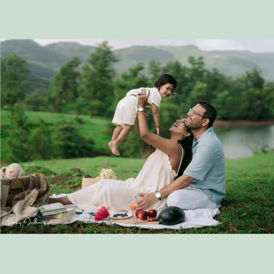 A moment of pure, high-flying joy! The mother lifts her son into the air during their family picnic, his happy face framed against the beautiful green hills.