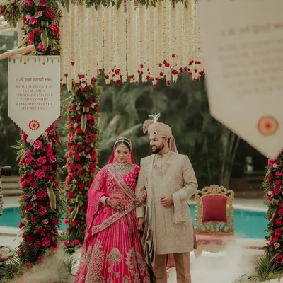 The couple stands united under a magnificent floral mandap, a portrait of grace and togetherness just after their Varmala exchange. The soft smoke at their feet adds a touch of magic to this traditional wedding photograph.