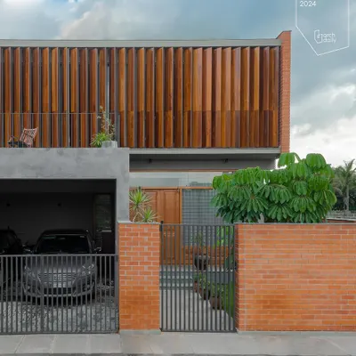 The front facade of the 'Screen House' features a large, operable wooden screen on the upper floor. This allows the residents to control privacy and sunlight, while the combination of brick, concrete, and wood creates a warm, modern aesthetic.