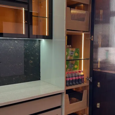 This tall unit combines a pantry with open shelving and pull-out wooden baskets. The integrated lighting ensures you can always see what you have, even at the very back.