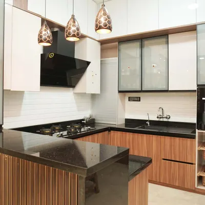 This open-plan kitchen features warm wood-finish cabinets and a breakfast bar with a black granite top, perfect for casual dining. The design is enhanced by stylish honeycomb pendant lights and white subway tile backsplash, blending classic and modern elements.