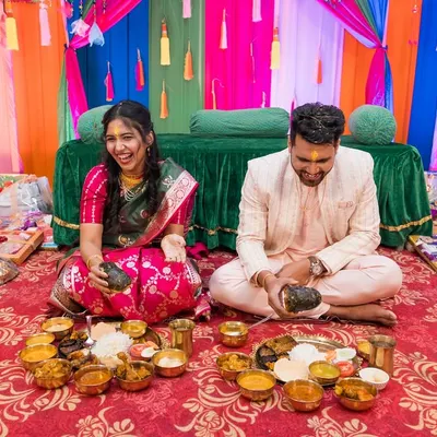 A candid moment of pure laughter during a pre-wedding ritual. The vibrant colors of the decor mirror the joy shared between the couple.