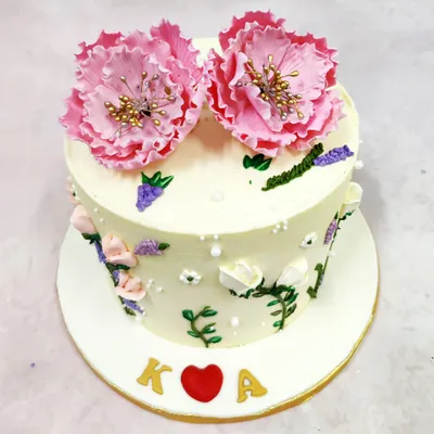 We paint a picture of romance with this hand-painted flower cake. Delicate pink blooms, resembling peonies, crown the cake, while smaller blossoms and leaves are artfully painted onto the buttercream, creating a piece of edible art for an intimate celebration.