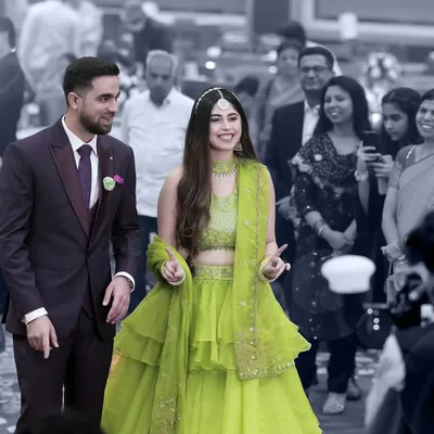 The couple makes their grand entrance at the Sangeet. The selective color effect puts the focus squarely on them, highlighting their joy amidst the crowd.